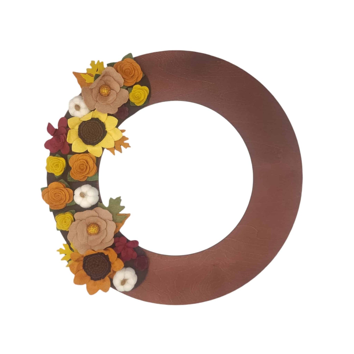 A decorative wreath featuring vibrant sunflowers, pumpkins, and assorted autumn-hued flowers set on a deep brown backdrop on a walnut wreath base