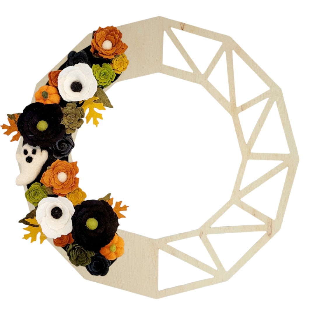 Playful little felted ghosts peek out among the colorful blooms, adding a whimsical touch to the door hanger decor.