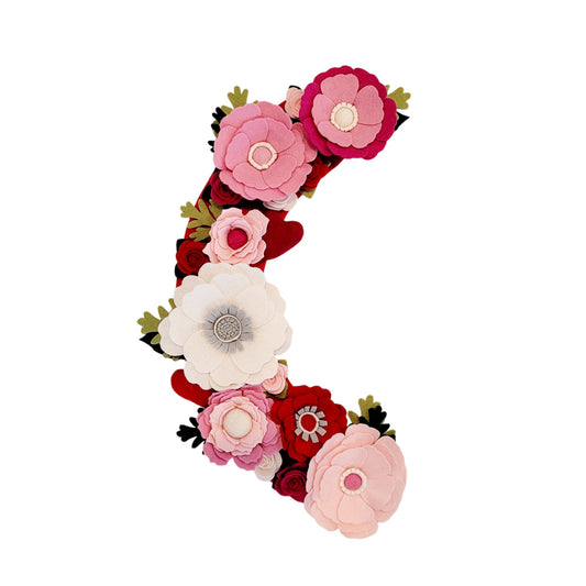 A Valentine’s Day wreath made with wool felt flowers in beautiful shades of pink, creating a soft and romantic aesthetic.