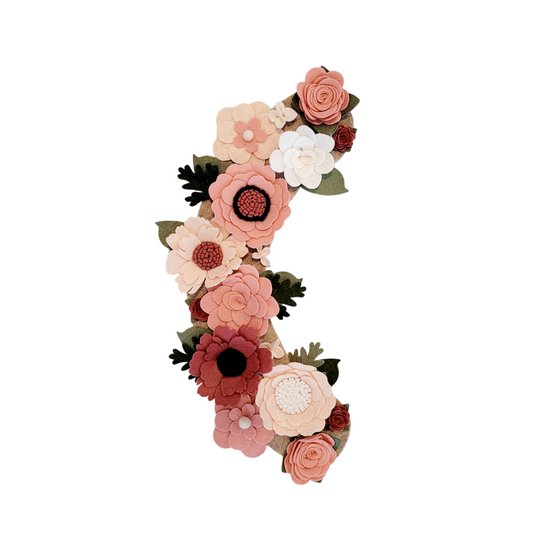 Interchangeable spring wreath is full of pink, blush, and linen flowers on a beige background.
