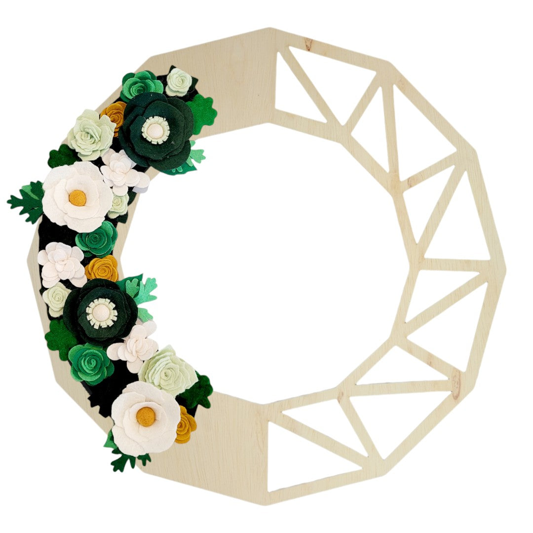 A St. Patrick's Day wreath made with green, white, and gold felt flowers, celebrating the spirit of the holiday shown on a birch geometric base.