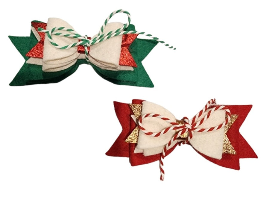 The Reusable Bow Set | Holiday Edition - Set of 2 is depicted on a white background, featuring two festive bows made of layered felt in holiday colors. The top bow consists of green and white felt with red glitter accents, tied with a green and white striped string. The bottom bow is crafted from red and white felt with gold glitter accents, tied with a red and white striped string.
