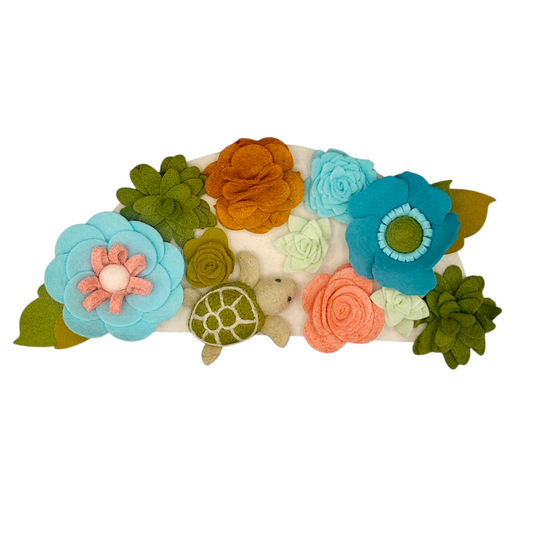 Wreath attachment featuring a sea turtle surrounded by seaweed and blue, turquoise, and green flowers on a sand-colored base.