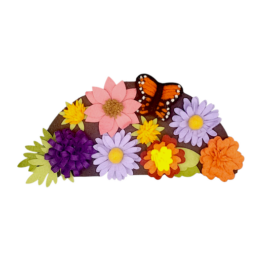Close-up of a fall wreath attachment adorned with monarch butterflies and colorful blooms like asters, lantana, milkweed, and marigolds on a brown background.