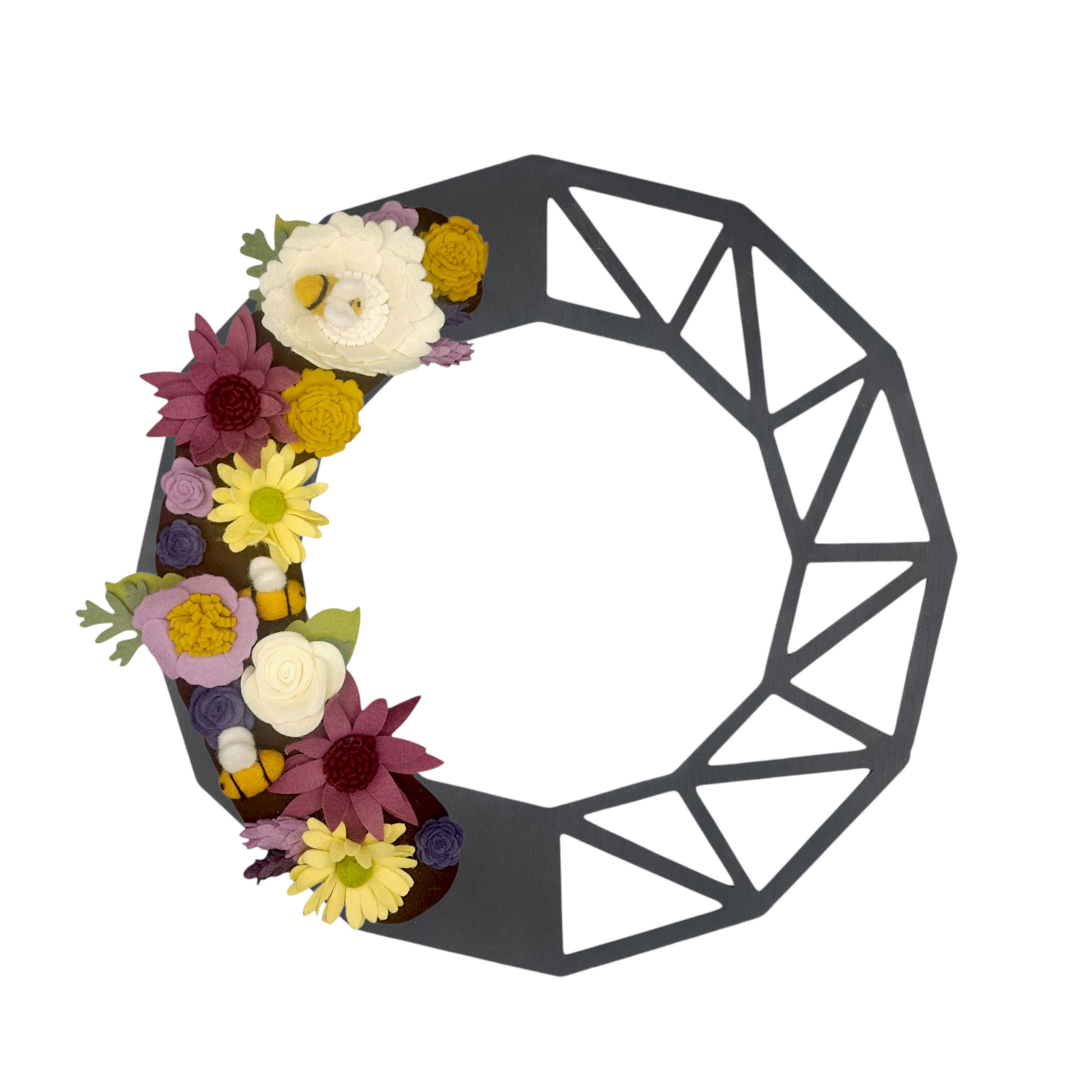 This charming wreath promotes the "Save the Bees" movement, featuring delightful felt bees buzzing among vibrant purple and yellow flowers on a black geometric base.