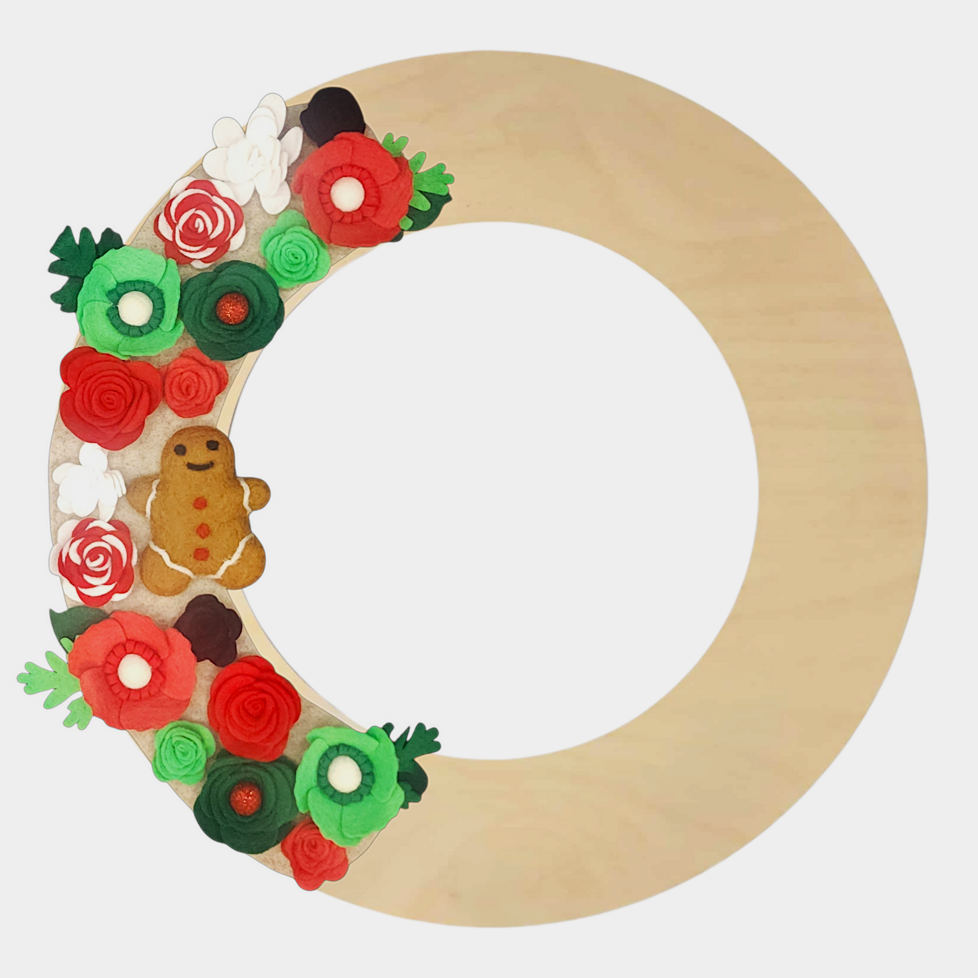 Seasonal wreath with eco-friendly materials, featuring candy cane flowers, cheerful green and red blooms, and a festive gingerbread on a beige felt on a birch wreath base