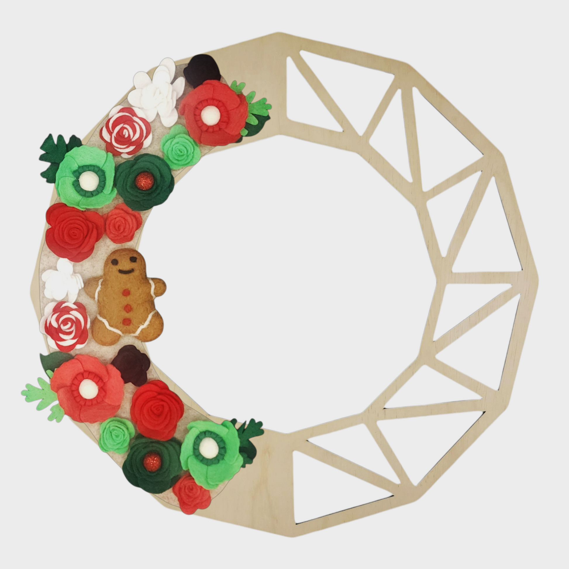 Interchangeable holiday wreath featuring candy cane-inspired flowers, bright green and red blooms, and a gingerbread accent on a neutral beige backdrop on a geometric wreath