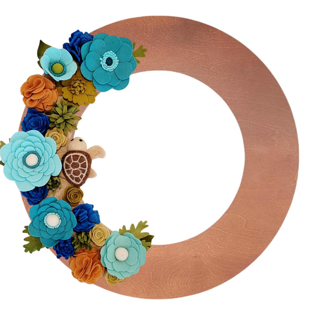 An eco-friendly wreath supporting the "Save the Sea Turtles" cause, featuring bright teal, green, and brown felt flowers.