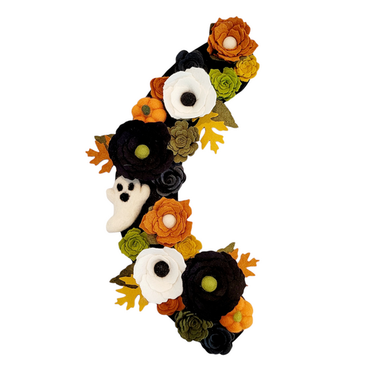 Adorable orange felted pumpkins are nestled throughout the wreath, enhancing its festive charm.