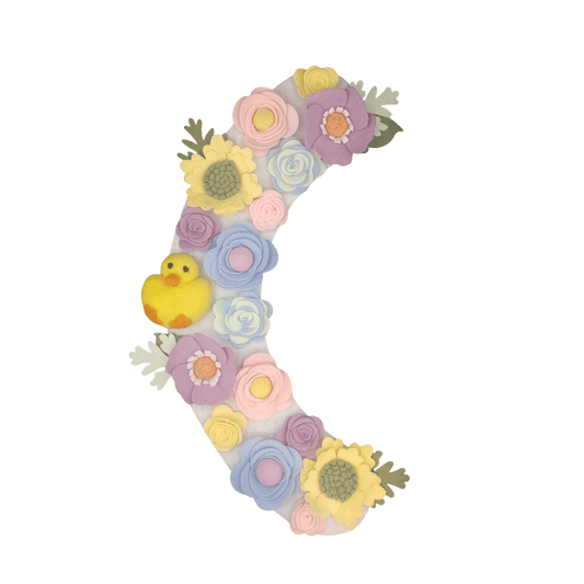 Limited release Easter wreath attachment decorated with pastel flowers in soft yellow, pink, purple, and baby blue tones, symbolizing spring renewal. A charming felted chick is nestled among the blooms, adding a playful and festive touch to this seasonal design.
