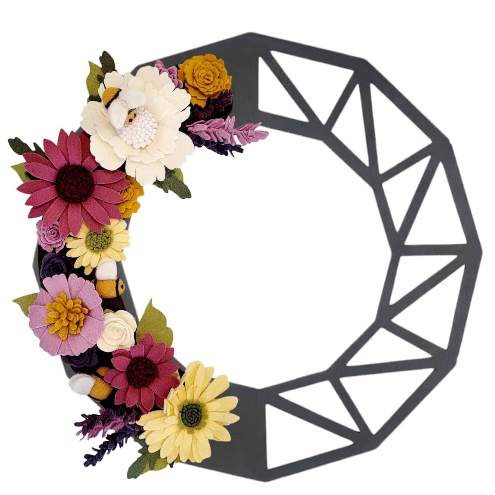 This charming wreath promotes the "Save the Bees" movement, featuring delightful felt bees buzzing among vibrant purple and yellow flowers on a black geometric base.