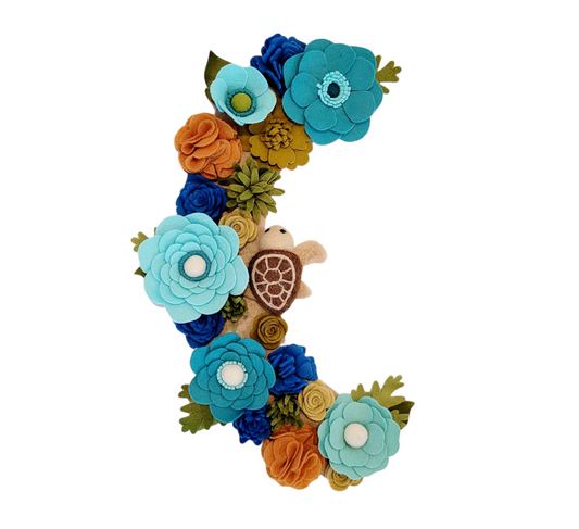 The Save the Sea Turtles wreath attachment is adorned with a seat turtle, seaweed, and lots of flowers! With shades of blue, turquoise, and green flowers on a sand-colored background. *A percentage of the proceeds will go towards protecting these beautiful sea creatures.