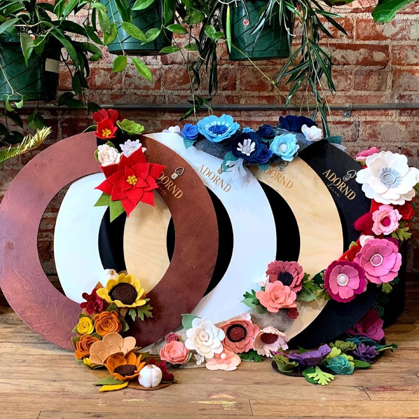 18" Wreath bases in all four colors shown with a variety of decorative attachments hanging around the bases. Wooden wreath base, felt flowers, handmade flowers, decorative attachments. 
